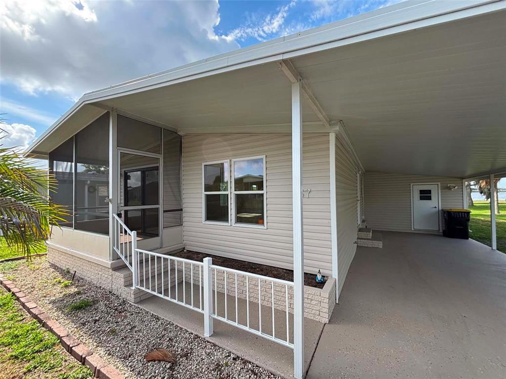 A mobile home exterior features a screened porch, a carport, and light-colored vinyl siding — 1901 US HIGHWAY 17 92, LAKE ALFRED, FL