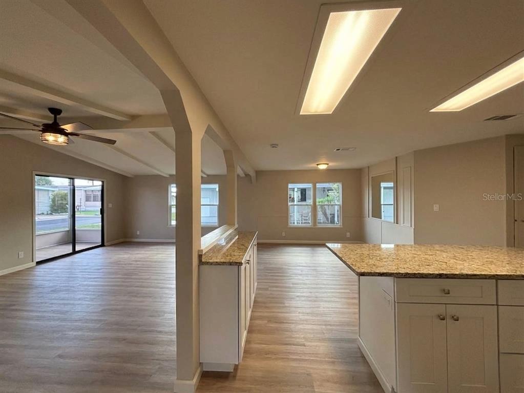 A kitchen with granite countertops overlooks a living area with light wood-look flooring — 1901 US HIGHWAY 17 92, LAKE ALFRED, FL