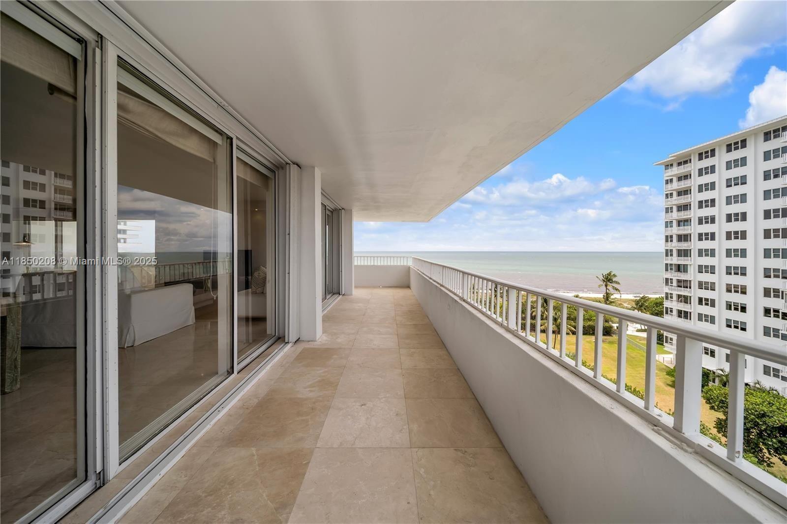 A long, tiled balcony overlooks the ocean and a neighboring high-rise building — 199 Ocean Lane Dr # 901, Key Biscayne FL 33149, KEY BISCAYNE, FL