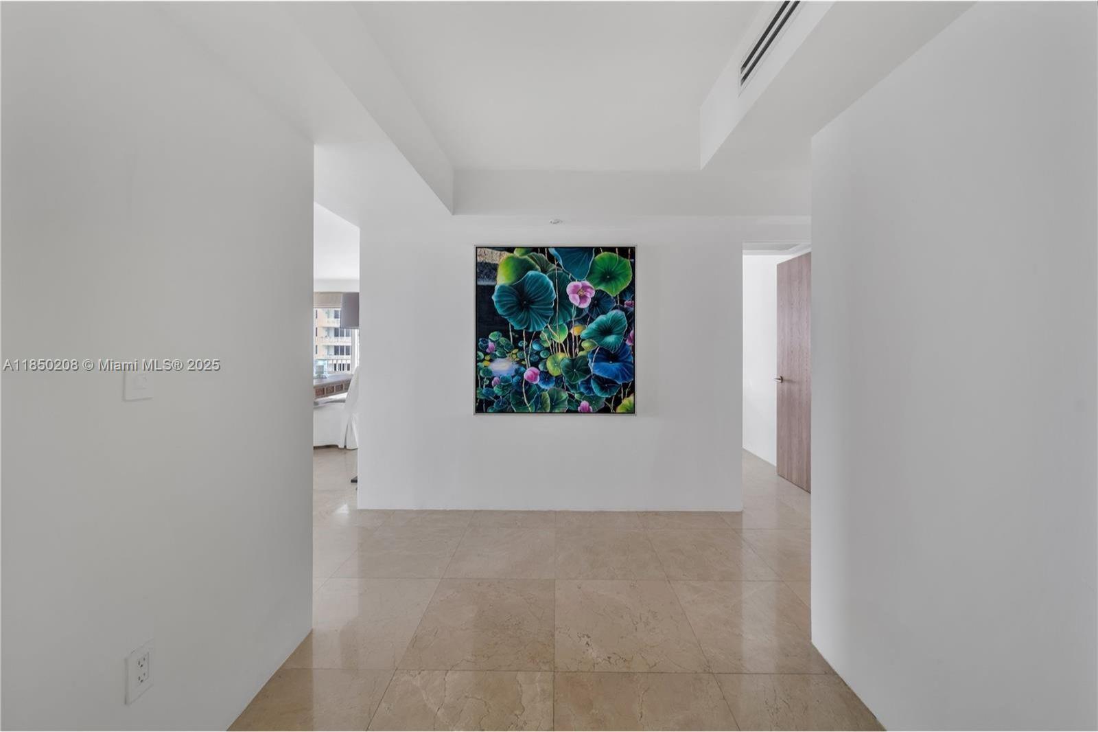 A bright hallway with beige tile flooring features a large floral painting on the wall — 199 Ocean Lane Dr # 901, Key Biscayne FL 33149, KEY BISCAYNE, FL