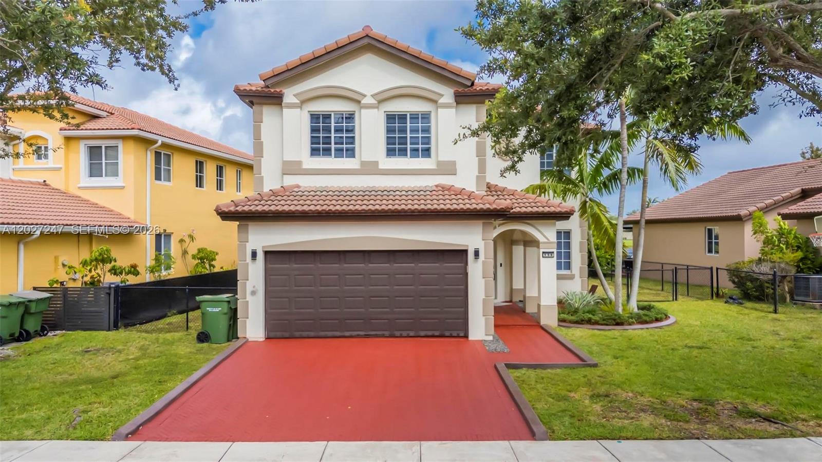 A two-story house features a brown garage door, a red driveway, and a tiled roof — 156 SE 22nd Ter, Homestead FL 33033, HOMESTEAD, FL