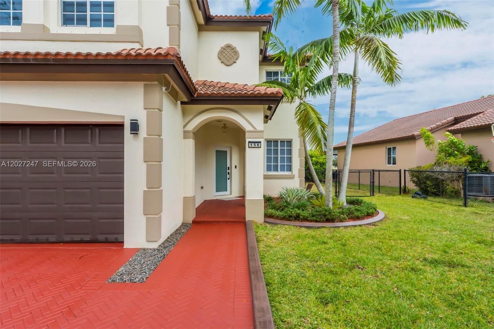 The exterior of a two-story house features a red brick walkway and a palm tree — 156 SE 22nd Ter, Homestead FL 33033, HOMESTEAD, FL