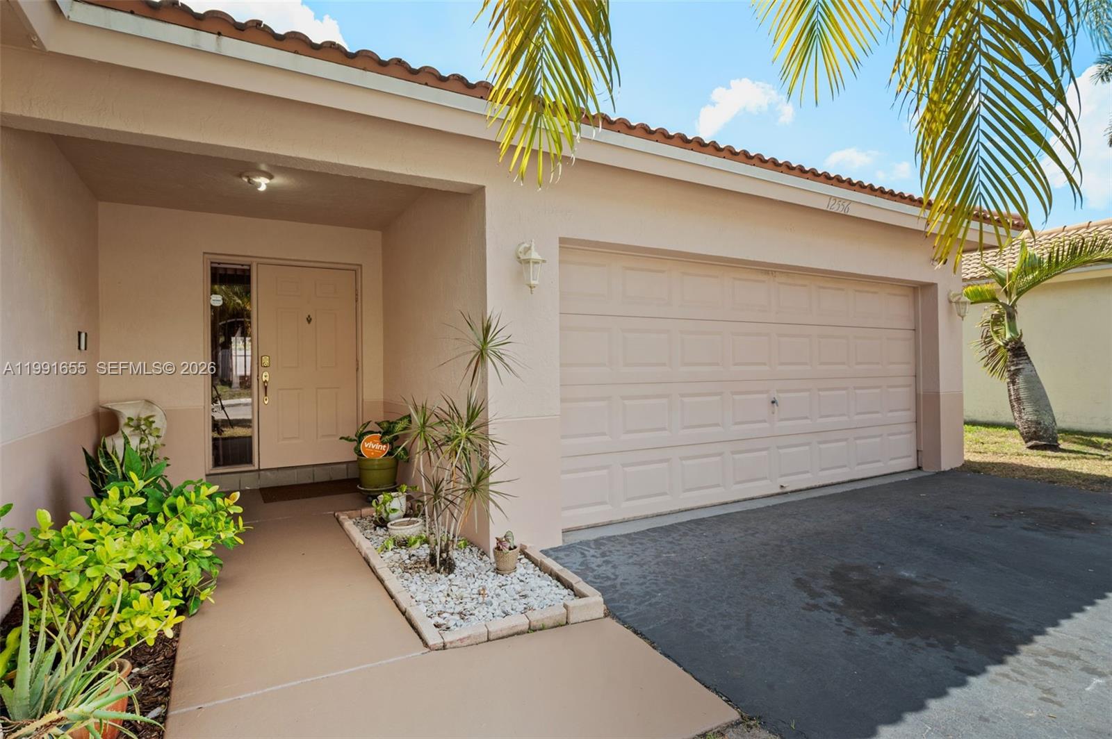 The exterior of a single-story house features a tan stucco facade, garage, and front entrance — 12556 NW 10th Pl, Sunrise FL 33323, SUNRISE, FL