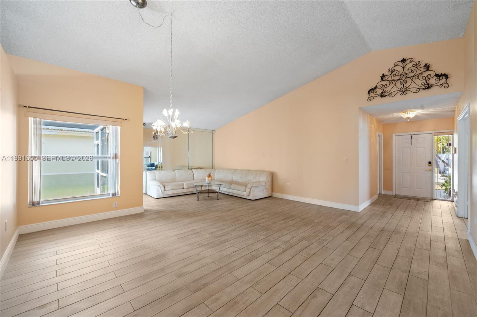 A living room features light wood-look tile flooring, peach walls, and a large sectional sofa — 12556 NW 10th Pl, Sunrise FL 33323, SUNRISE, FL