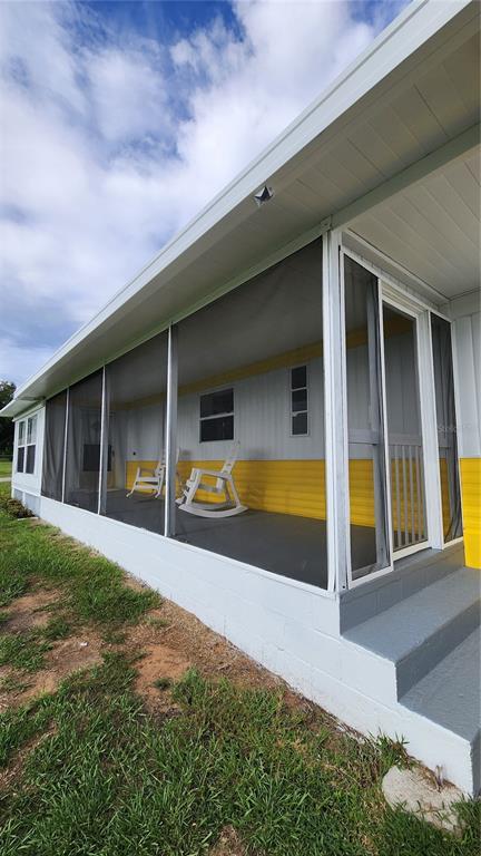 A screened-in porch with white rocking chairs sits on a concrete foundation beside a house — 17653 BROAD STREET, MONTVERDE, FL