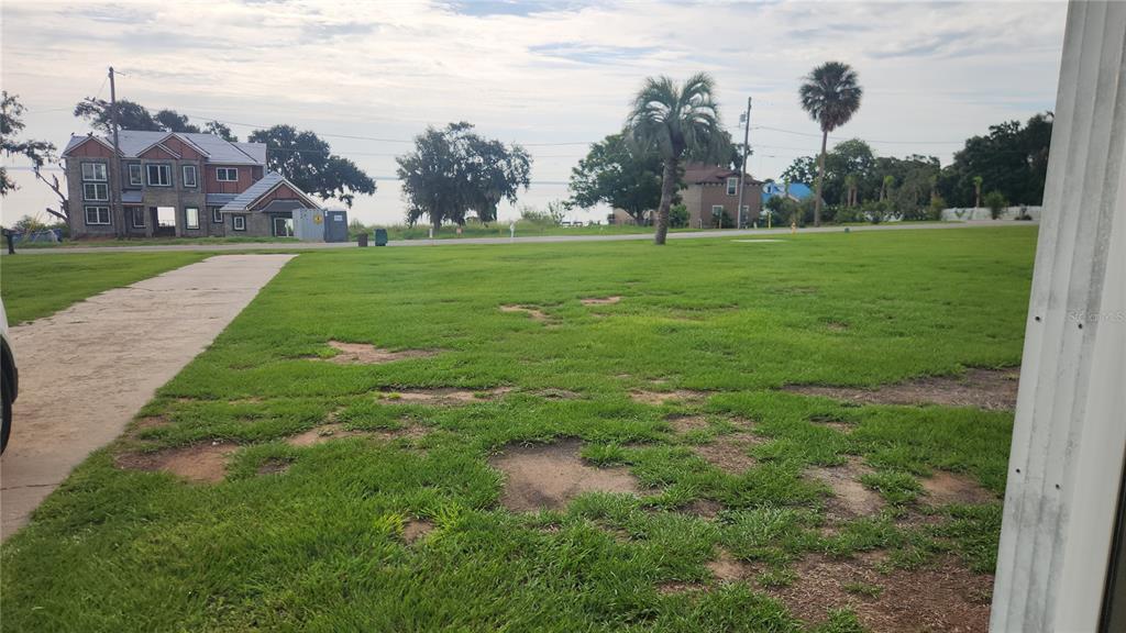 A grassy lot with a concrete driveway leads toward a house near a body of water — 17653 BROAD STREET, MONTVERDE, FL