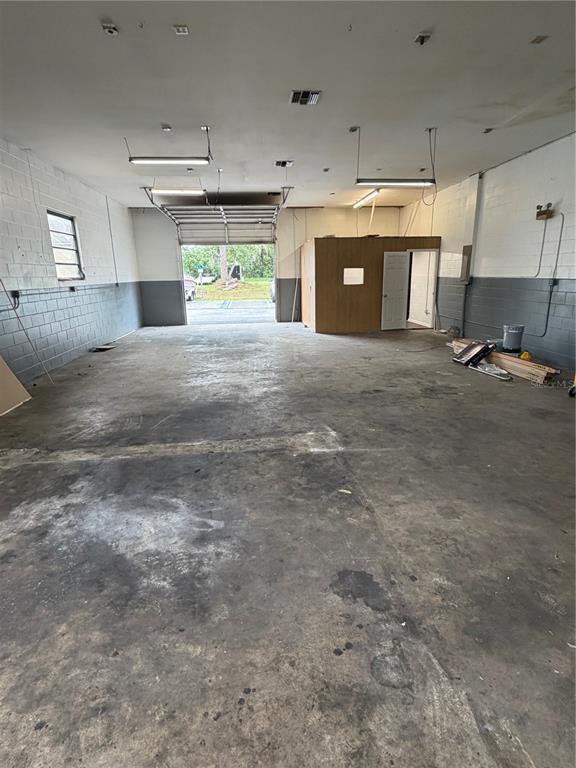 An empty industrial warehouse space features concrete floors, block walls, and a roll-up garage door — 4500 NE 35TH STREET UNIT G-28, OCALA, FL