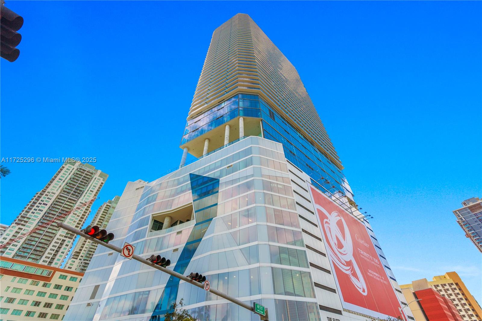 A low-angle view of a modern skyscraper with a large red advertisement on its facade — 398 NE 5th St # 3207, Miami FL 33132, MIAMI, FL
