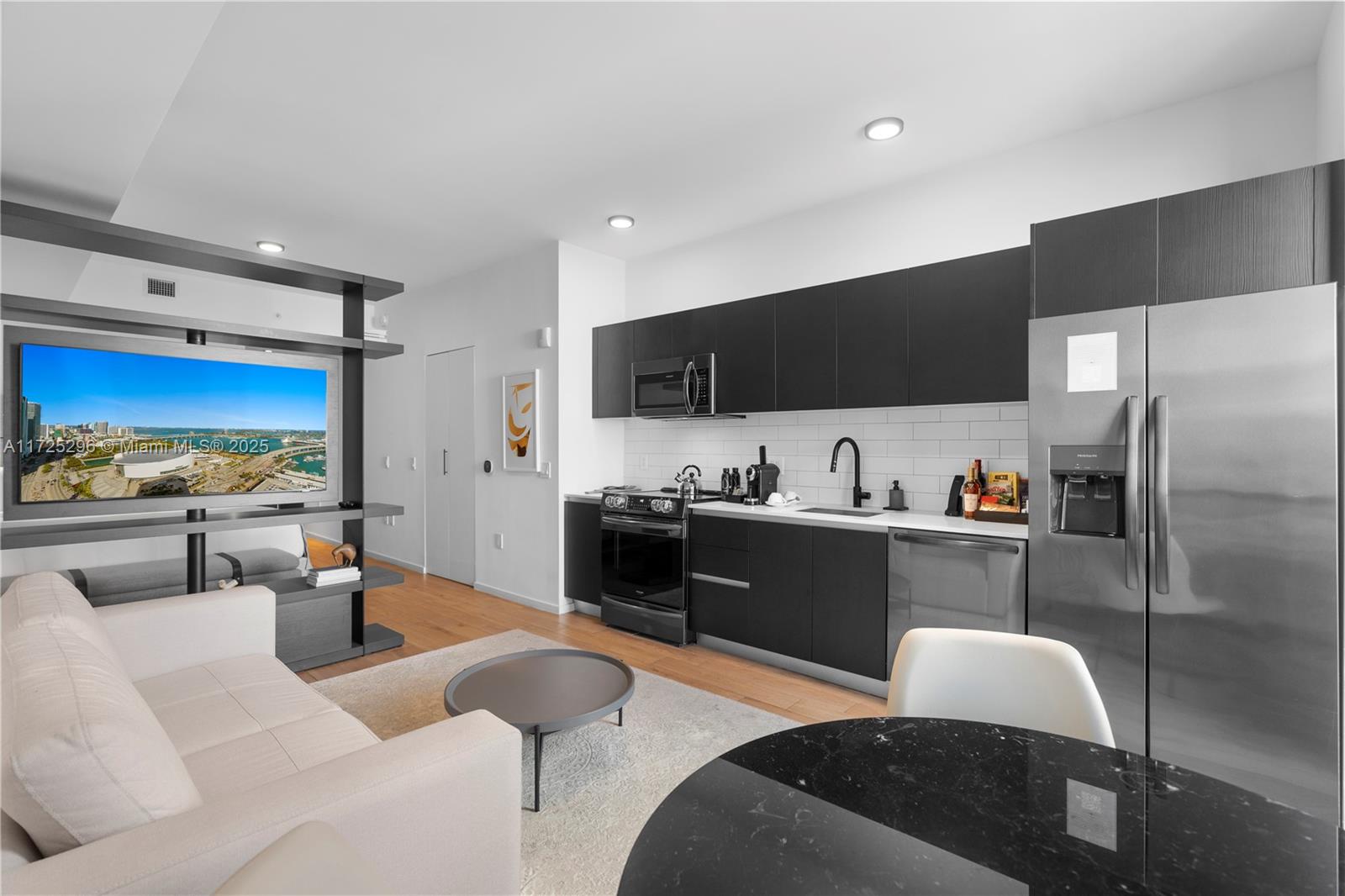A modern studio apartment features a kitchen with dark cabinetry, stainless appliances, and a living area — 398 NE 5th St # 3207, Miami FL 33132, MIAMI, FL