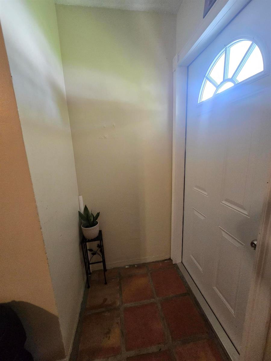 An entryway with terracotta tile flooring, a white door with a window, and a plant stand — 3560 NW 3rd Avenue # 2, Pompano Beach FL 33064, POMPANO BEACH, FL