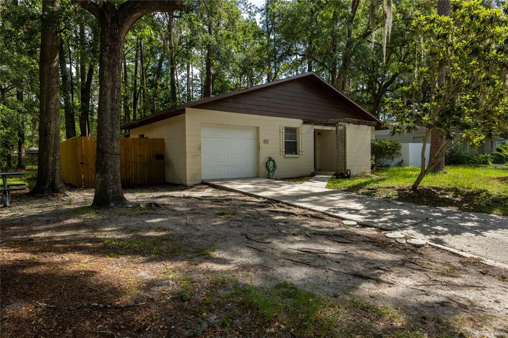 A single-story house with a garage, light-colored siding, and a brown roof in a wooded area — 2902 NW 39TH PLACE, GAINESVILLE, FL