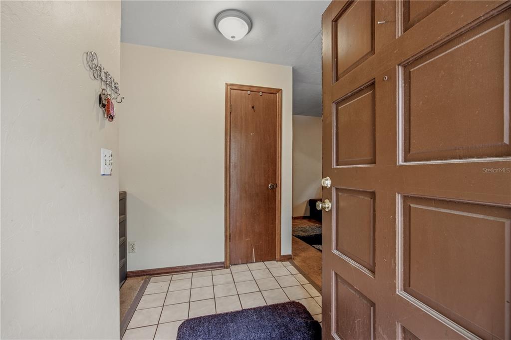An entryway features a brown paneled door, tiled floor, and a closed wooden closet door — 2902 NW 39TH PLACE, GAINESVILLE, FL