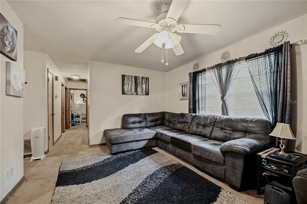 A living room features a grey sectional sofa, a patterned area rug, and a ceiling fan — 2902 NW 39TH PLACE, GAINESVILLE, FL