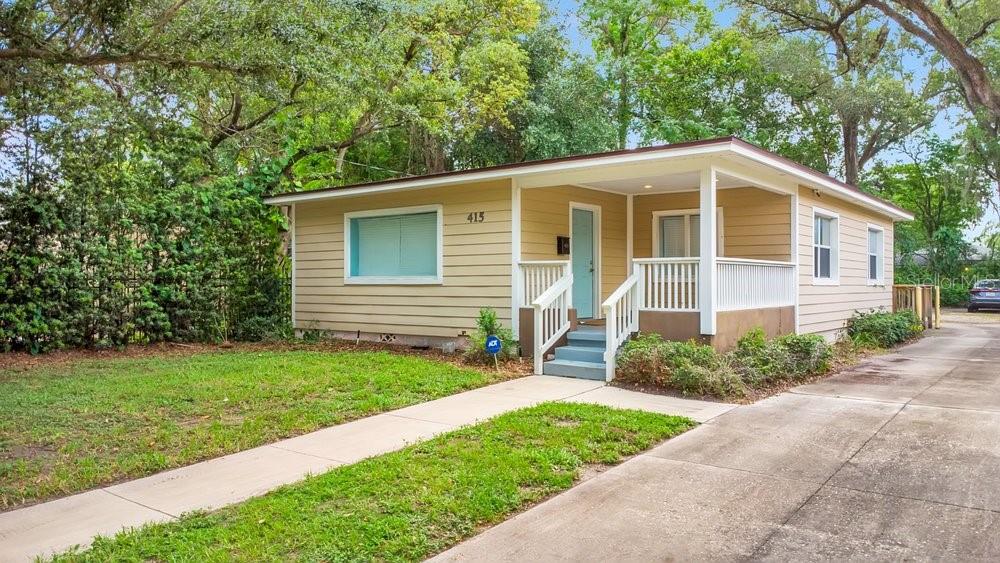 A single-story house with tan horizontal siding, a front porch, and a concrete driveway — 415 S SUMMERLIN AVENUE, ORLANDO, FL