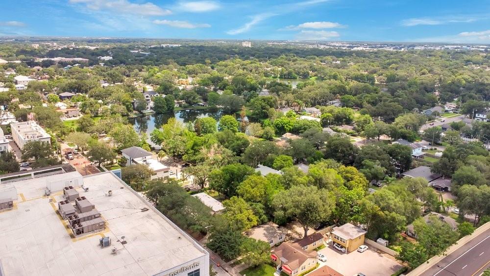 An aerial view shows a commercial building rooftop, surrounding houses, and a small lake — 415 S SUMMERLIN AVENUE, ORLANDO, FL