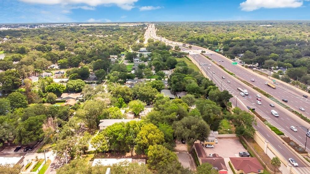 An aerial view shows a multi-lane highway running alongside a residential area with many trees — 415 S SUMMERLIN AVENUE, ORLANDO, FL