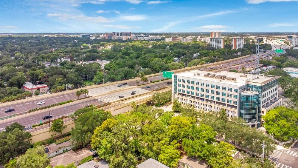 An aerial view shows a multi-story office building adjacent to a highway and trees — 415 S SUMMERLIN AVENUE, ORLANDO, FL