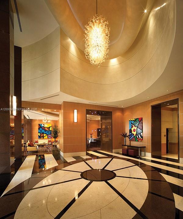 A grand lobby features a large glass chandelier, curved walls, and a patterned stone floor — 244 Biscayne Blvd # 2907, Miami FL 33132, MIAMI, FL