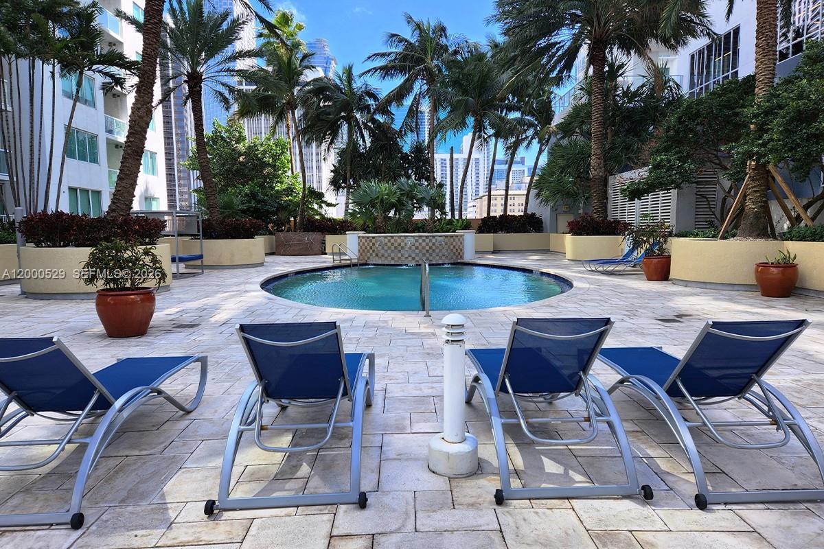 A circular pool sits on a stone patio surrounded by lounge chairs and palm trees — 244 Biscayne Blvd # 2907, Miami FL 33132, MIAMI, FL