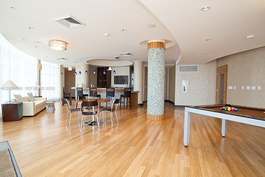 A spacious room features hardwood floors, a pool table, a bar area, and seating — 244 Biscayne Blvd # 2907, Miami FL 33132, MIAMI, FL