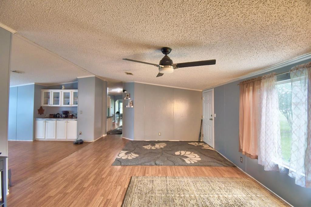 A living room with wood-look flooring, a ceiling fan, and a view into the kitchen — 1750 W FROSTPROOF ROAD, FROSTPROOF, FL