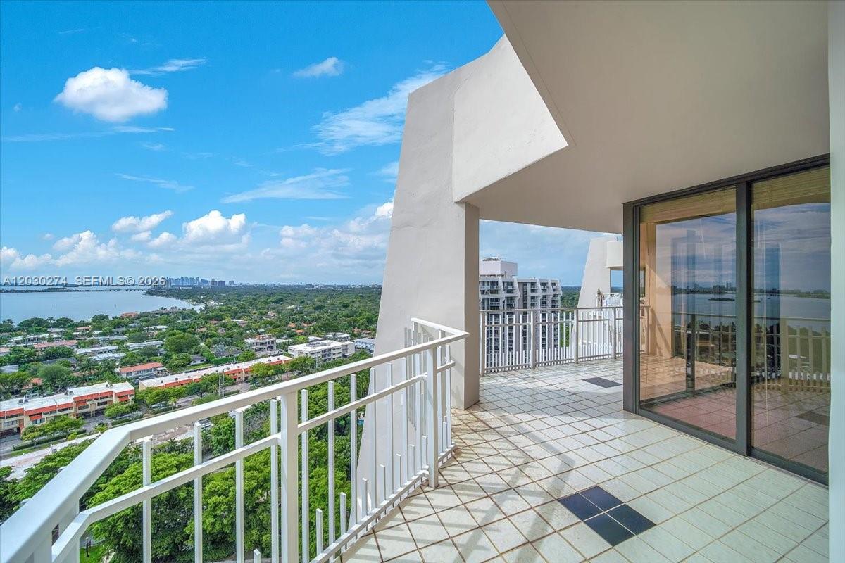 A high-rise balcony features white railings, tiled flooring, and expansive views of the surrounding landscape — 1000 Quayside Ter # 10, Miami FL 33138, MIAMI, FL