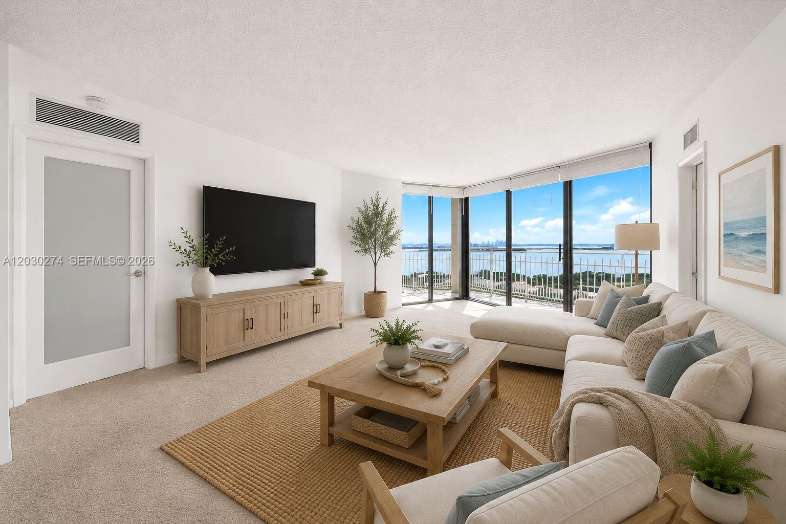 A bright living room features a sectional sofa, wooden furniture, and floor-to-ceiling windows overlooking water — 1000 Quayside Ter # 10, Miami FL 33138, MIAMI, FL