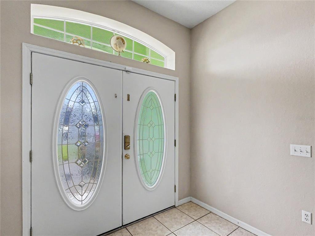 A foyer features double white doors with oval glass inserts and an arched transom window — 8155 WOODVINE CIRCLE, LAKELAND, FL