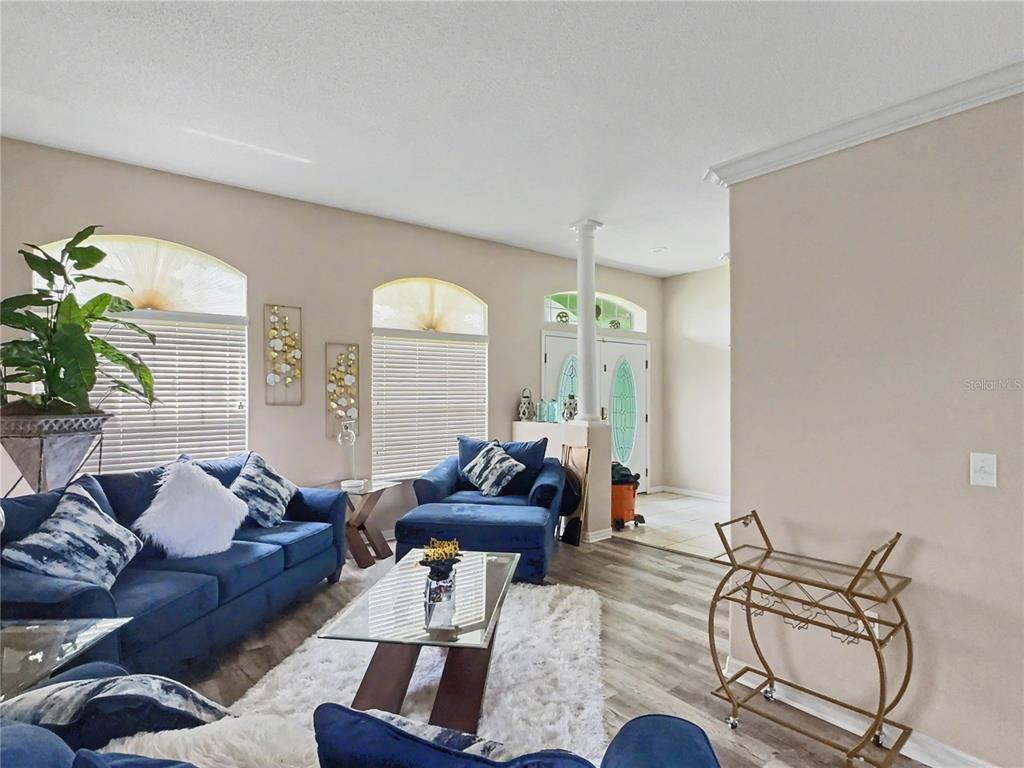 A living room features blue sofas, a glass coffee table, and a gold bar cart — 8155 WOODVINE CIRCLE, LAKELAND, FL