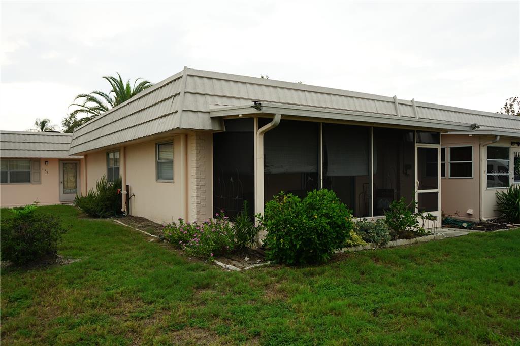 The exterior of a single-story home features a screened-in porch and a mansard roof — 201 BEDFORD TRAIL UNIT 138, SUN CITY CENTER, FL