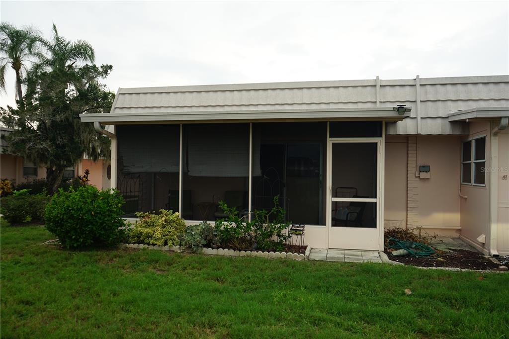 A screened-in patio with a sliding glass door sits attached to a light-colored house — 201 BEDFORD TRAIL UNIT 138, SUN CITY CENTER, FL