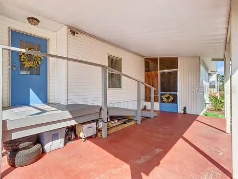 A covered porch with a red floor, a blue front door, and a wheelchair ramp — 8442 BREEZE HILL DRIVE, LAKE WALES, FL