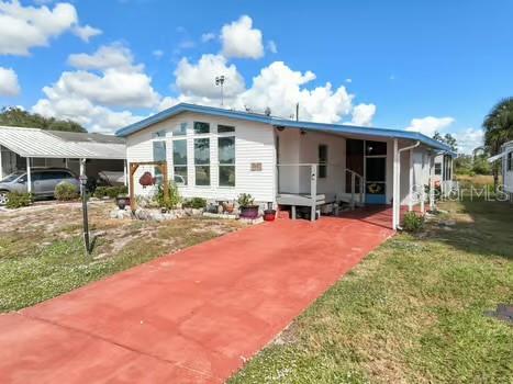 A single-story manufactured home with a red concrete driveway and a white exterior — 8442 BREEZE HILL DRIVE, LAKE WALES, FL
