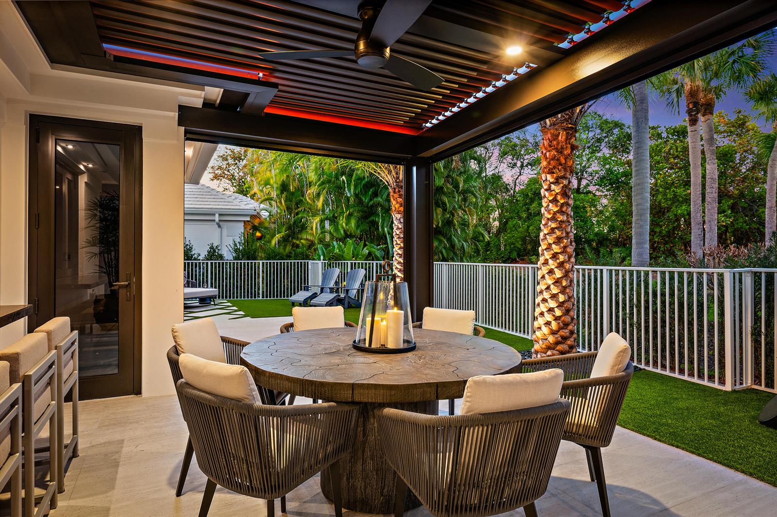 A covered outdoor dining area features a round wooden table, chairs, and a ceiling fan — 3501 Captains Way, Jupiter FL 33477, JUPITER, FL