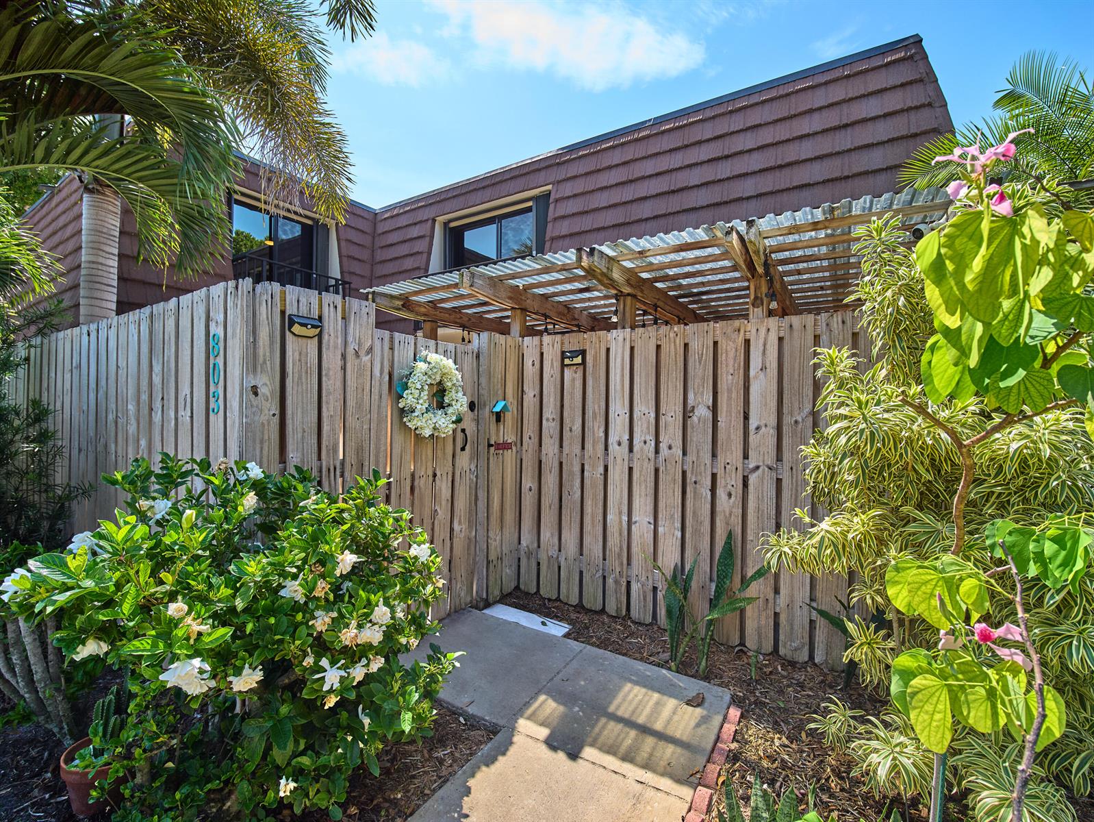 A wooden fence with a gate and pergola leads to the entrance of a house — 803 8th Lane, Palm Beach Gardens FL 33418, PALM BEACH GARDENS, FL