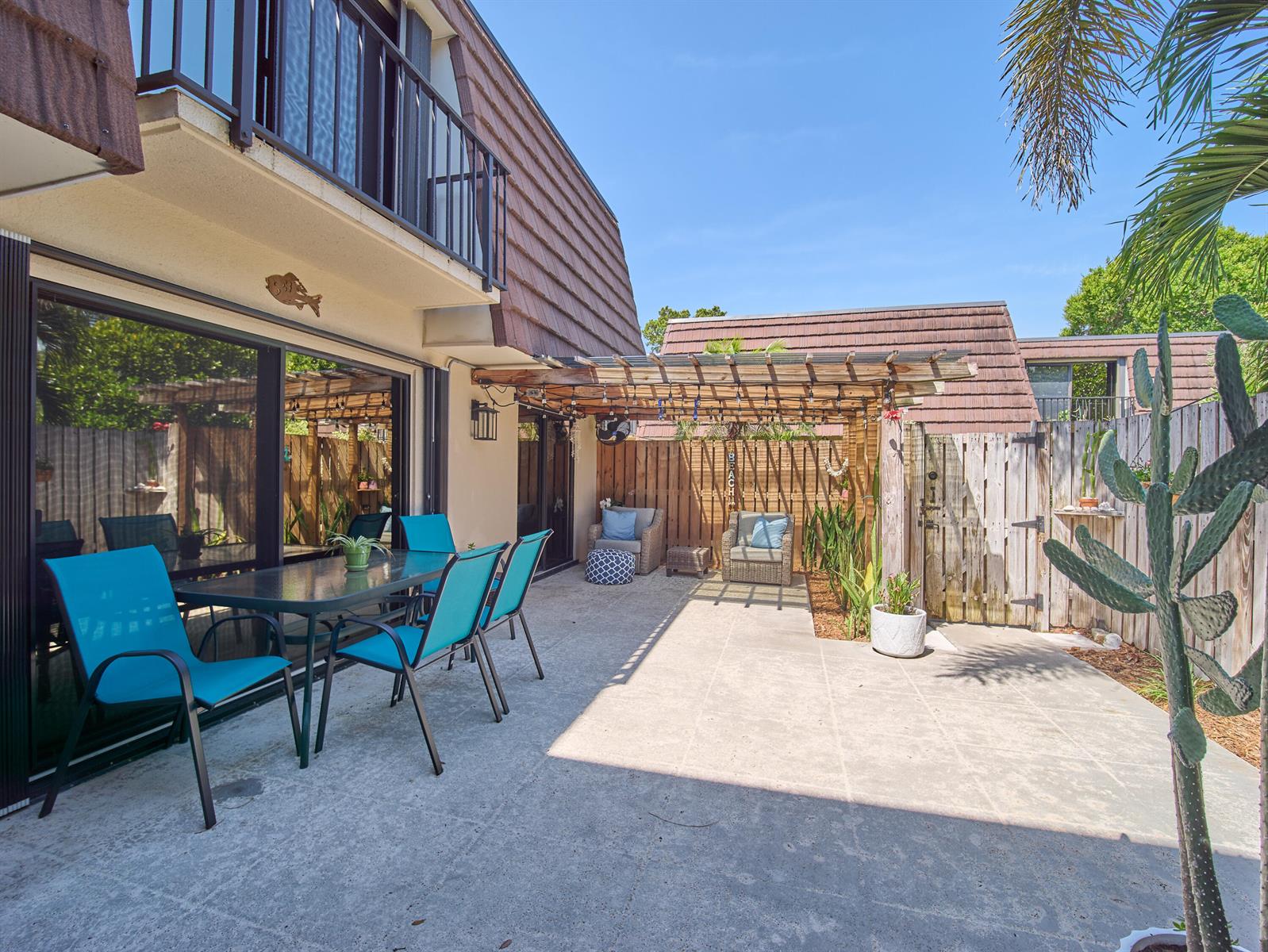 A patio with a pergola, outdoor dining set, and seating area next to a building — 803 8th Lane, Palm Beach Gardens FL 33418, PALM BEACH GARDENS, FL