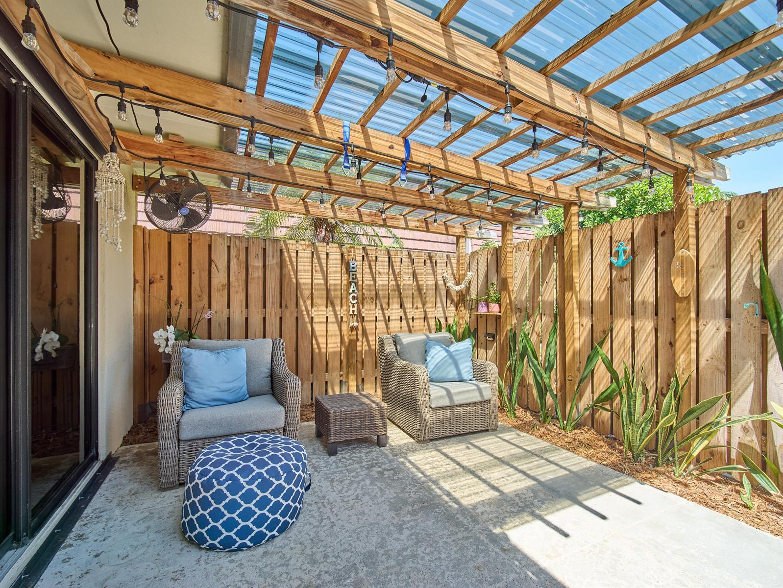 A patio features two wicker chairs, a small table, and a wooden pergola with lights — 803 8th Lane, Palm Beach Gardens FL 33418, PALM BEACH GARDENS, FL