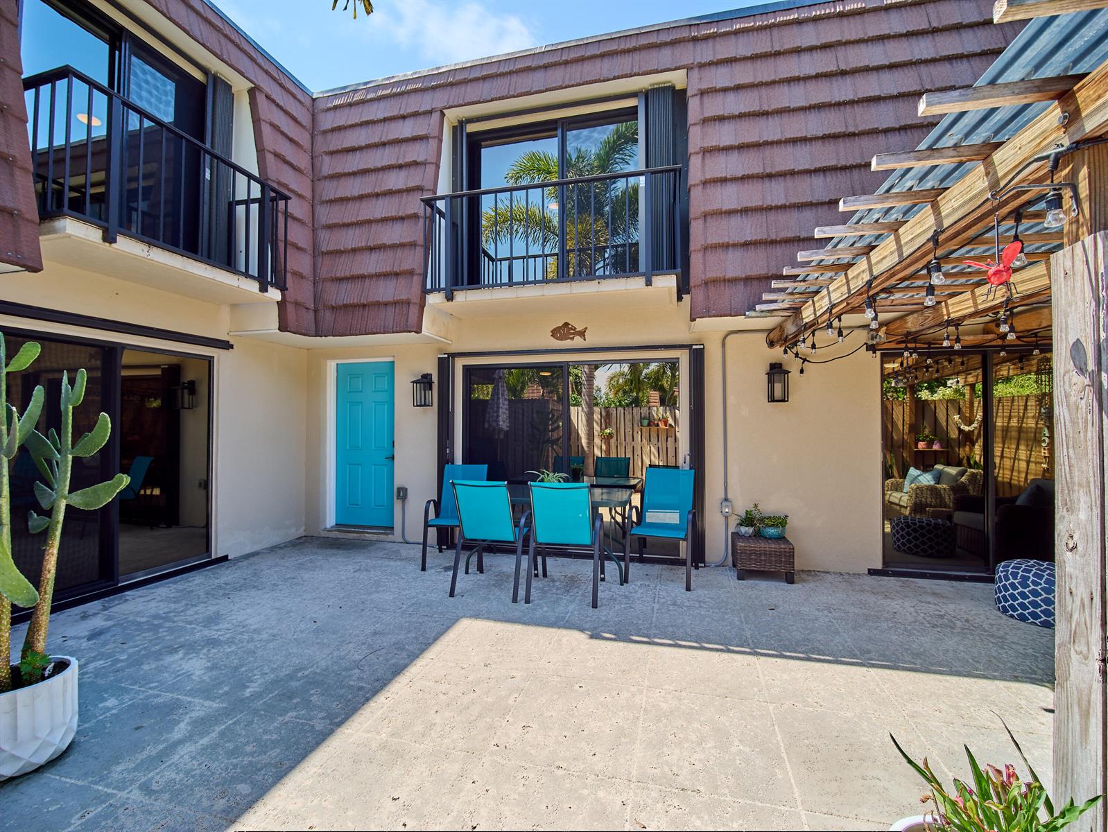 A concrete patio features a dining set, a bright blue door, and a wooden pergola — 803 8th Lane, Palm Beach Gardens FL 33418, PALM BEACH GARDENS, FL