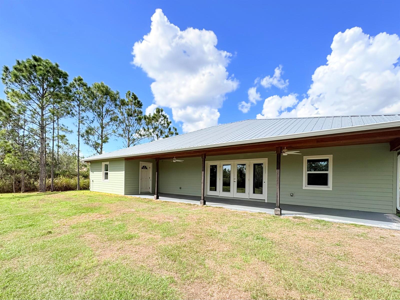 A light green house with a metal roof and a covered porch faces a lawn — 32801 Us-441 Lot 237, Okeechobee FL 34972, OKEECHOBEE, FL