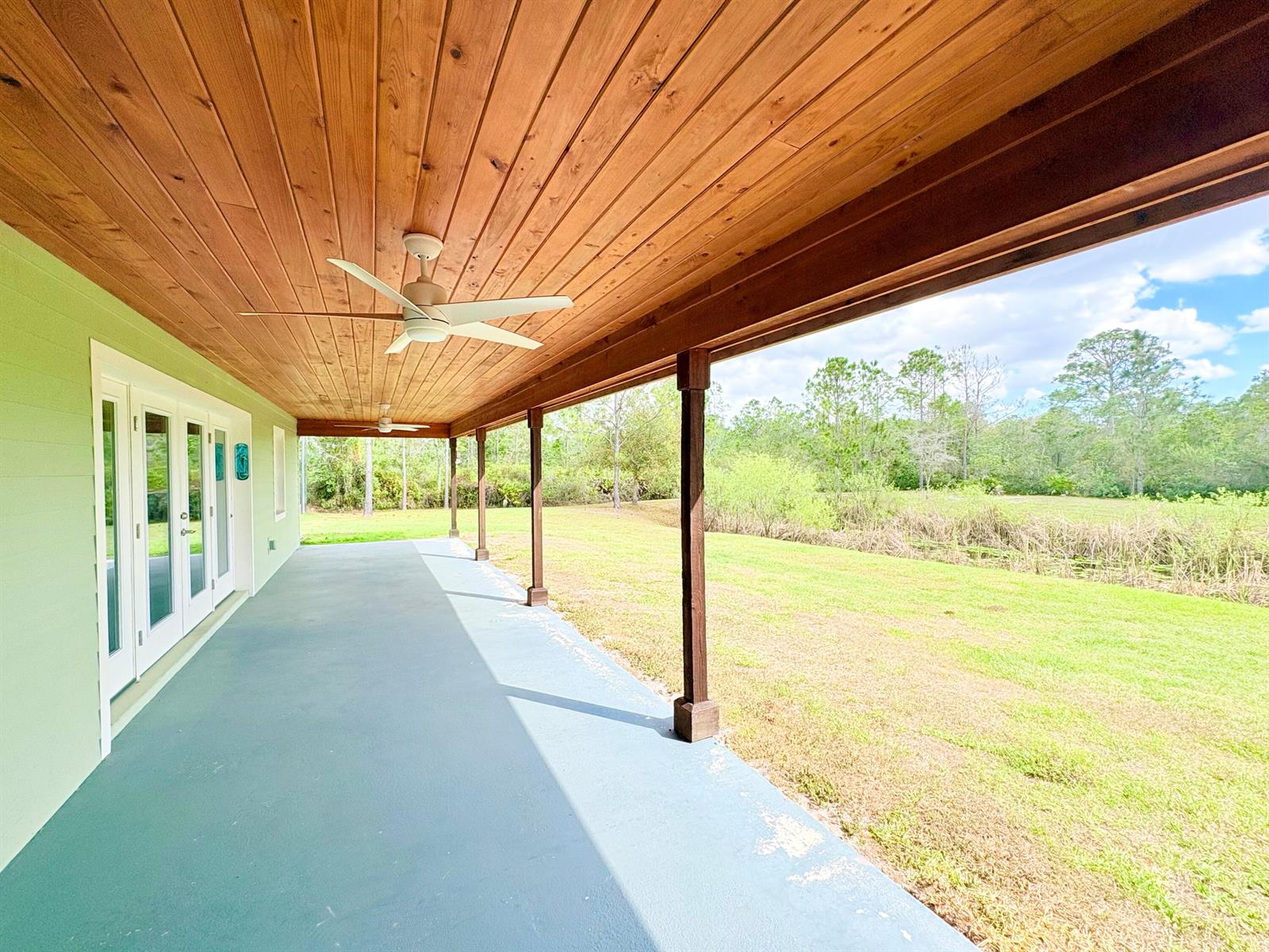 A covered porch with a wood-paneled ceiling, ceiling fans, and views of a grassy yard — 32801 Us-441 Lot 237, Okeechobee FL 34972, OKEECHOBEE, FL
