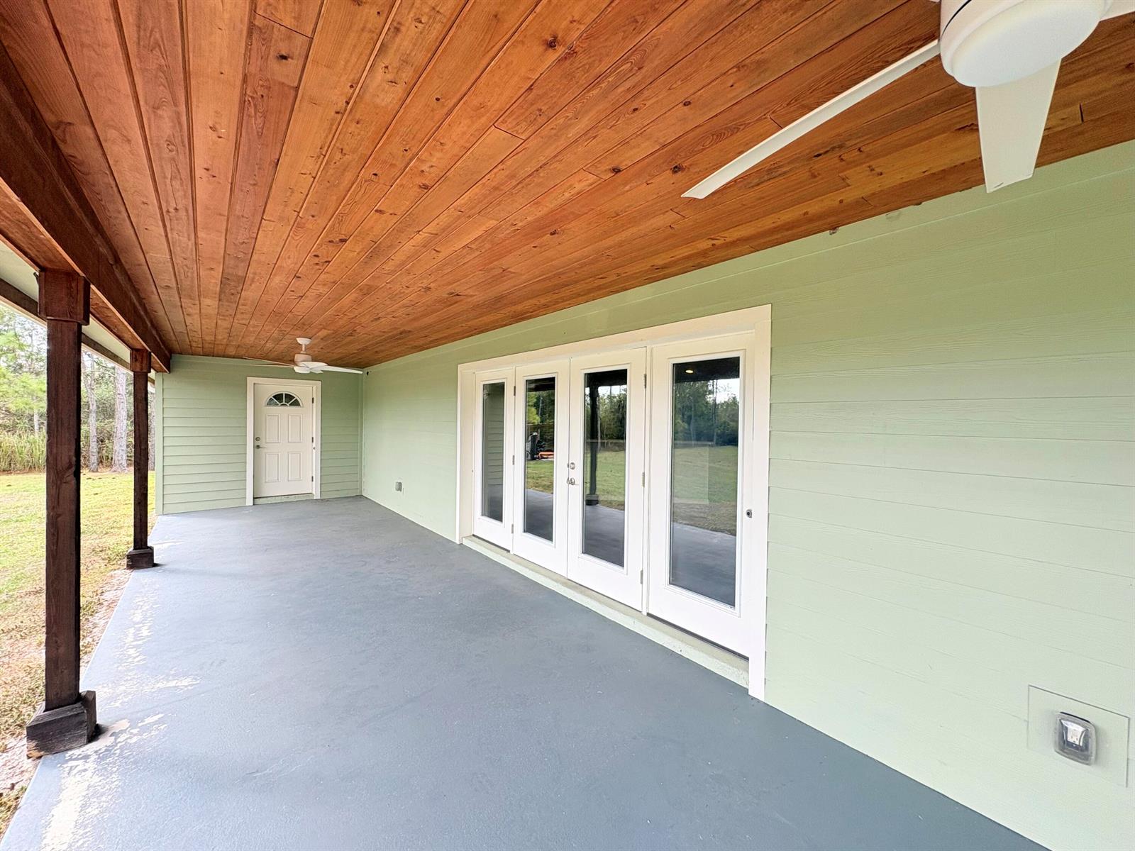 A covered porch with a wood ceiling, light green siding, and a set of glass doors — 32801 Us-441 Lot 237, Okeechobee FL 34972, OKEECHOBEE, FL