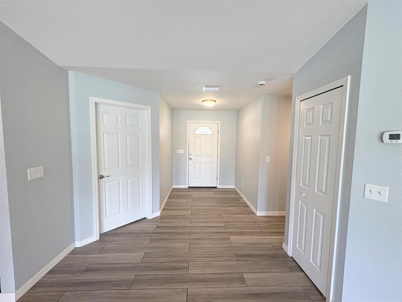 An entryway with light gray walls, wood-look tile flooring, and two white paneled doors — 32801 Us-441 Lot 237, Okeechobee FL 34972, OKEECHOBEE, FL