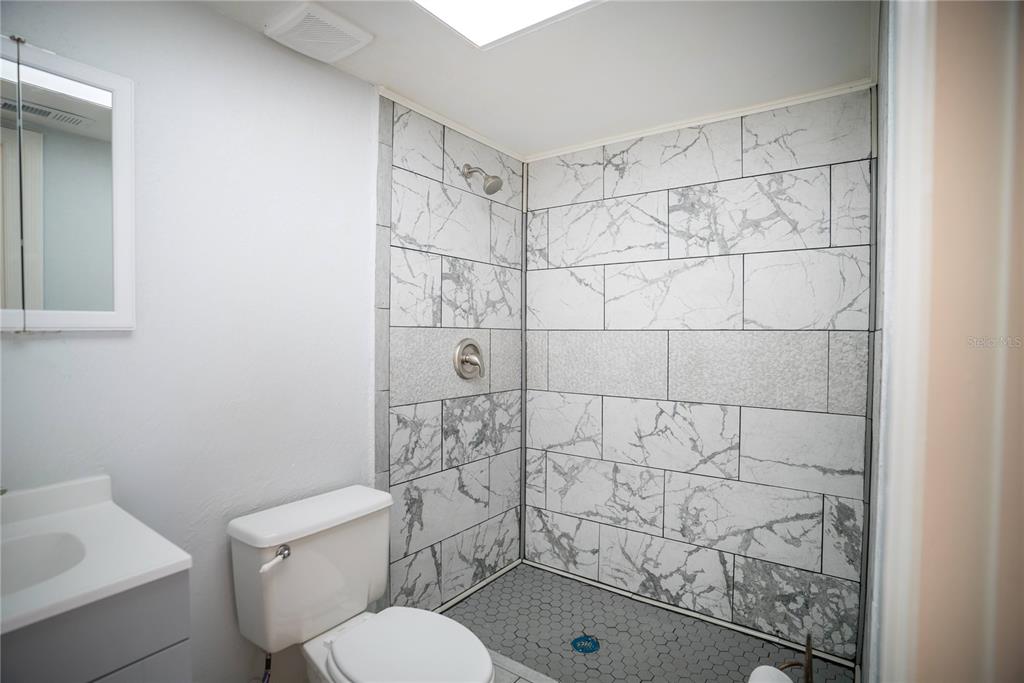 A bathroom features a walk-in shower with marble-look tile, a gray vanity, and a toilet — 3320 LAS BRISAS DRIVE, RIVERVIEW, FL