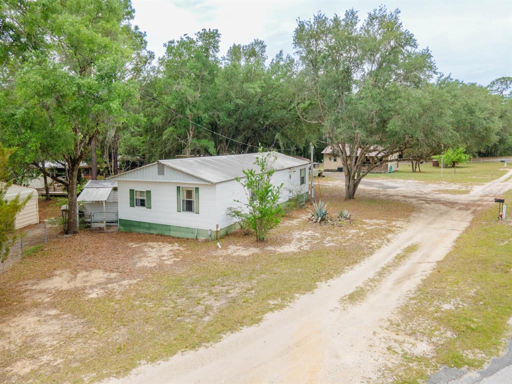 An exterior view of a white mobile home with a metal roof on a dirt lot — 21220 E HIGHWAY 316, FORT MC COY, FL