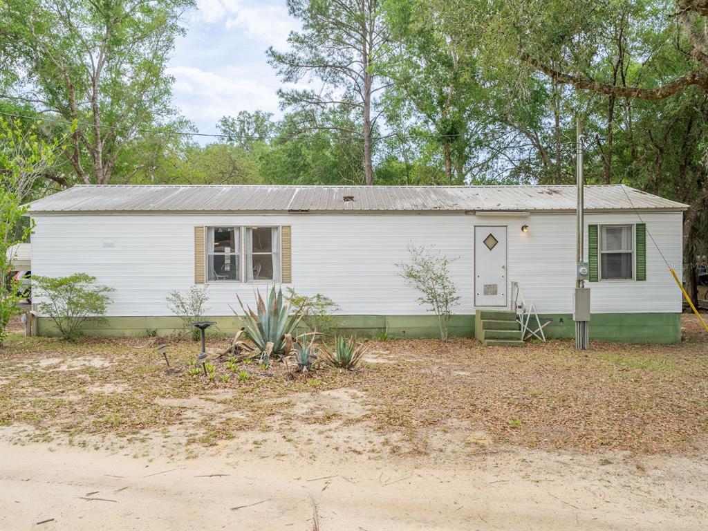 A single-story mobile home with white siding, green skirting, and a metal roof — 21220 E HIGHWAY 316, FORT MC COY, FL