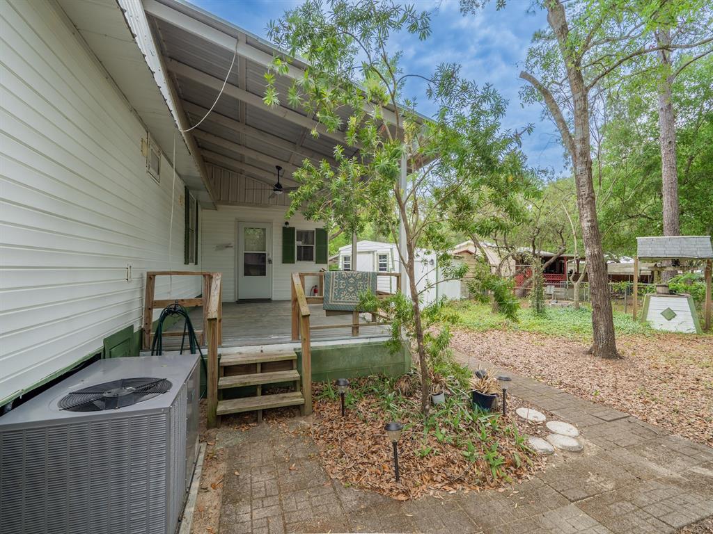A white house with a covered wooden porch, stairs, and a brick patio area — 21220 E HIGHWAY 316, FORT MC COY, FL