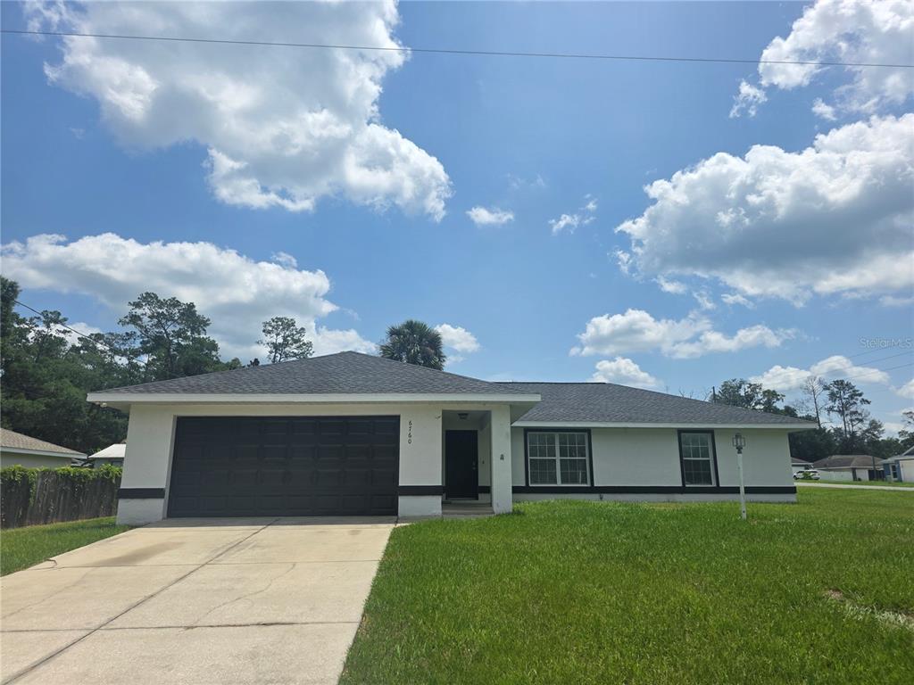 A single-story house with a dark garage door, white exterior, and a concrete driveway — 6760 CHERRY ROAD, OCALA, FL