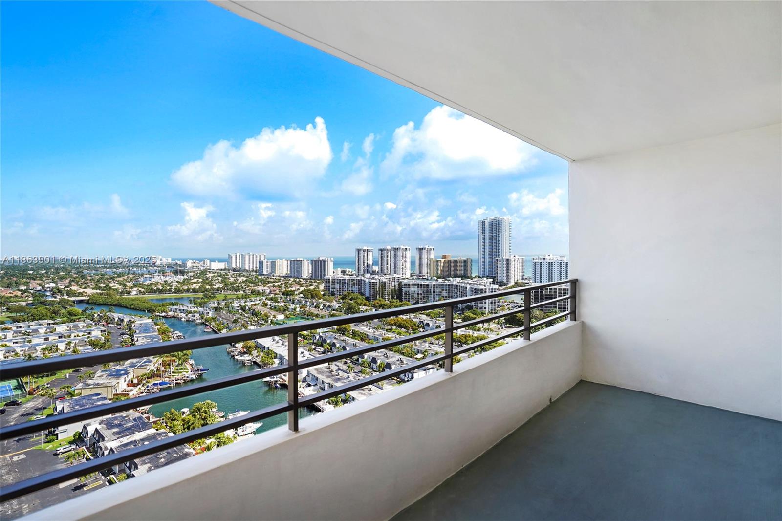 A high-rise balcony overlooks a canal, residential neighborhood, and distant city skyline — 2500 Parkview Dr # 2408, Hallandale Beach FL 33009, HALLANDALE BEACH, FL
