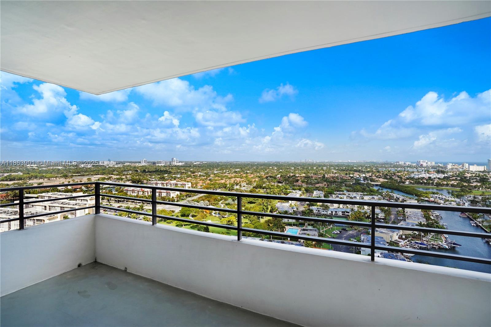 A high-rise balcony with a metal railing overlooks a suburban landscape and a waterway — 2500 Parkview Dr # 2408, Hallandale Beach FL 33009, HALLANDALE BEACH, FL