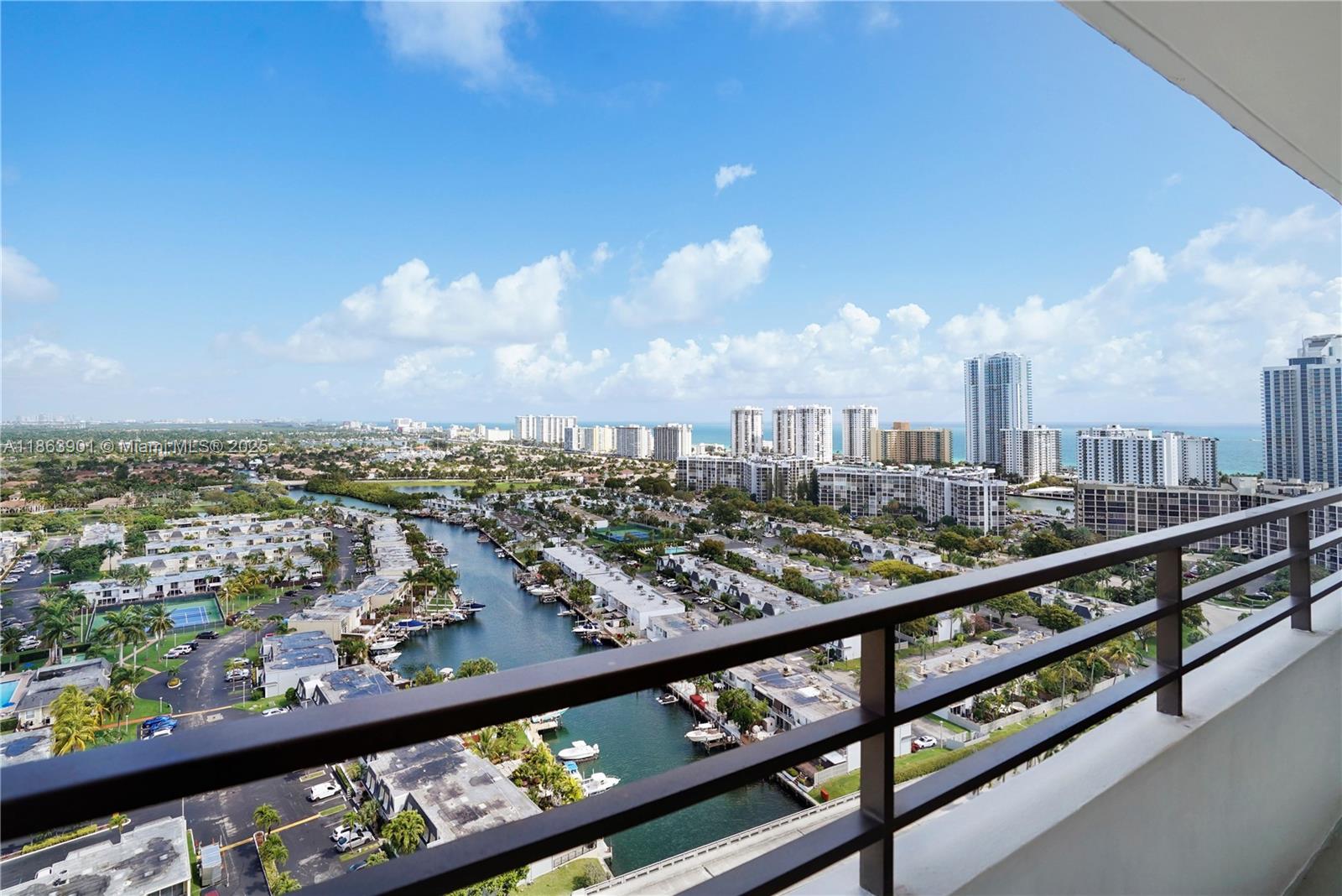 A high-angle view from a balcony overlooks a canal, residential buildings, and the ocean — 2500 Parkview Dr # 2408, Hallandale Beach FL 33009, HALLANDALE BEACH, FL